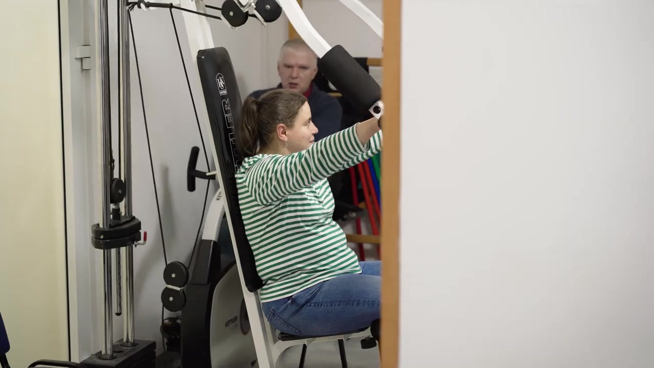 Uczestniczka ćwiczy na sprzęcie rehabilitacyjnym.