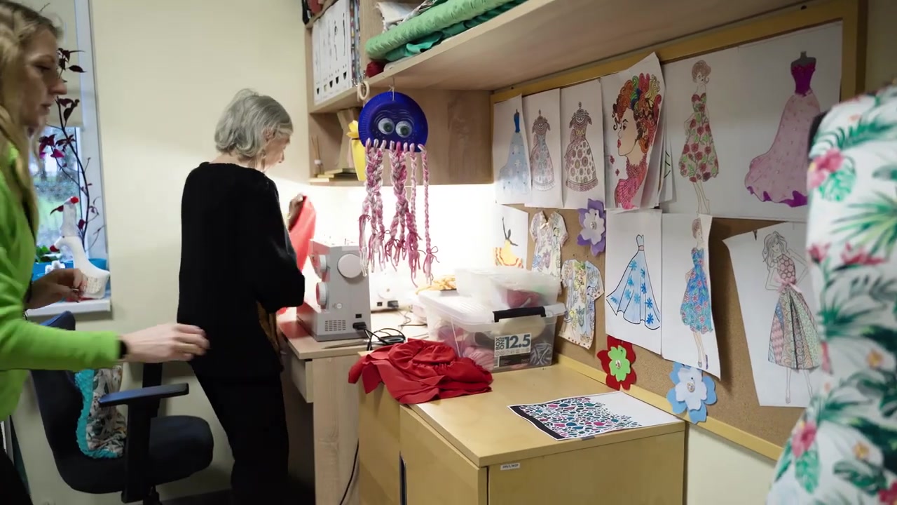 Osoba z zespołu pomaga uczestniczce w pracowni z pracami plastycznymi.