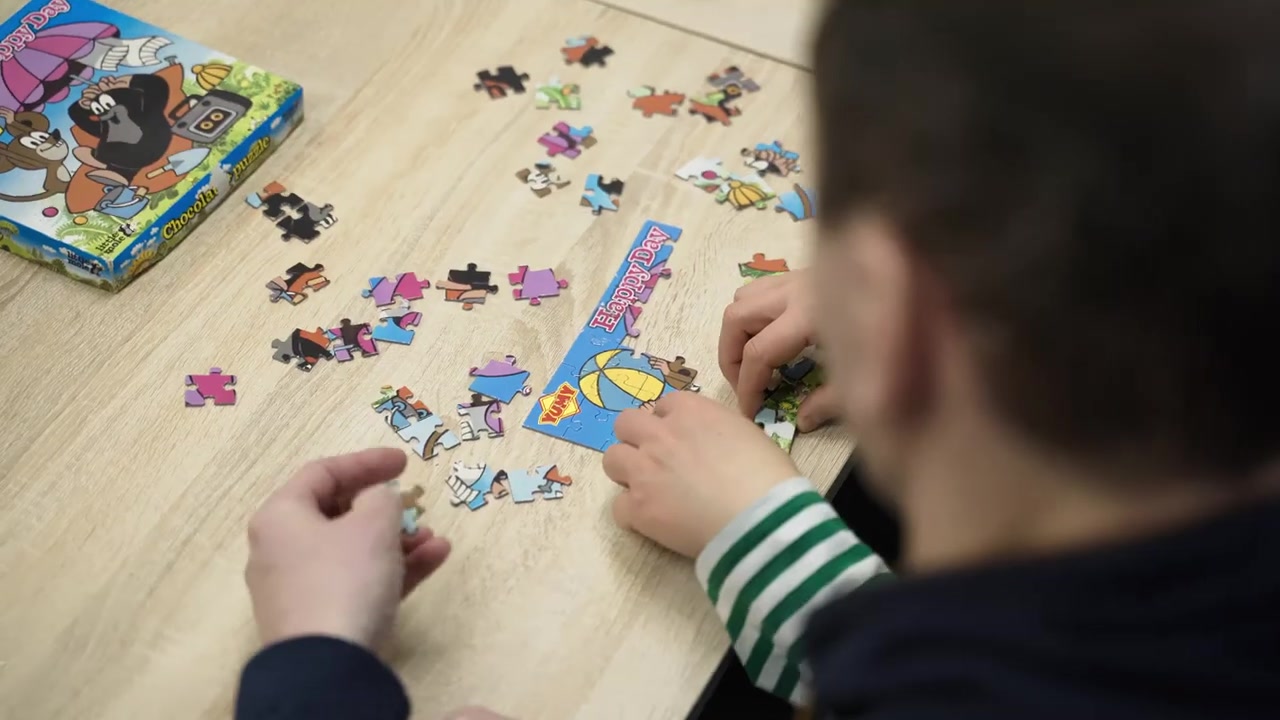 Uczestniczka układa puzzle przy stole.